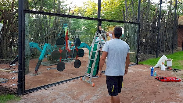 Nadrozměrná skla lvího výběhu v zoo, stroje, stromy, a štafle