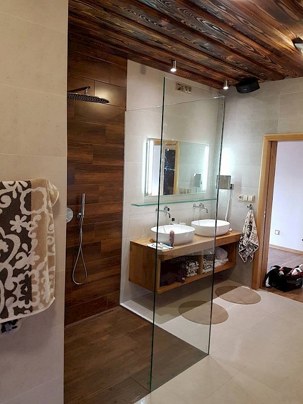 Moderní koupelna v kombinaci světlých a hnědých přírodních tónů se skleněnou zástěnou oddělující sprchový kout