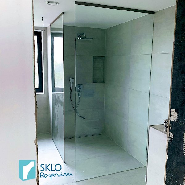 Moderní koupelna ve světlých tónech se skleněnou zástěnou oddělující sprchový kout