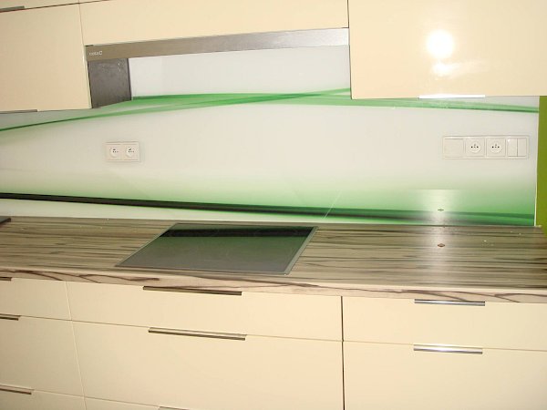 Skleněná deska do kuchyně s abstraktním bílo-zeleno-černým motivem za kuchyňskou linkou