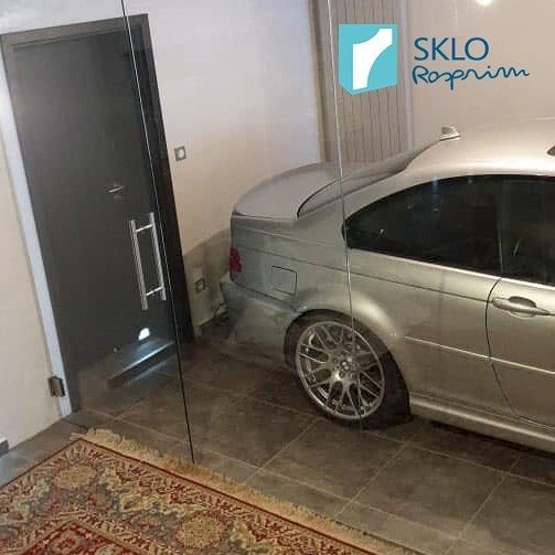 Skleněná zástěna se skleněnými dveřmi oddělující garáž od zbytku interiéru, průhled na stříbrné auto