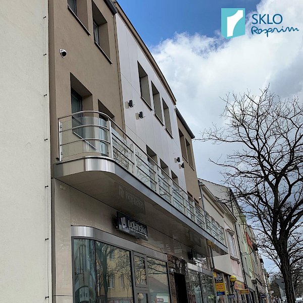 Dlouhé zaoblené skleněné zábradlí balkonů bytového domu