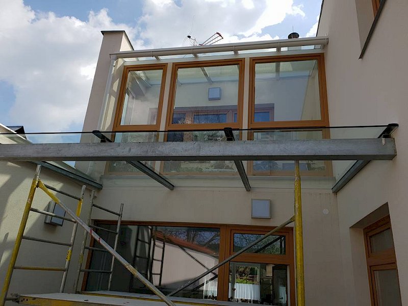 Zasklená lodžie na domě s okny s hnědými rámy