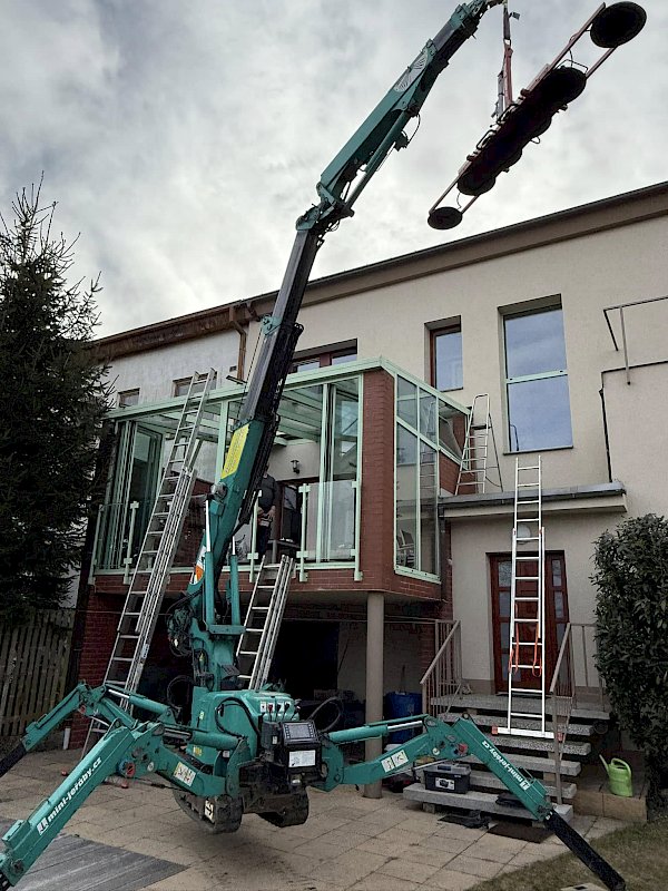 Proces zasklívání lodžie se speciální technikovou k uchytávání a přemisťování velkých skleněných ploch